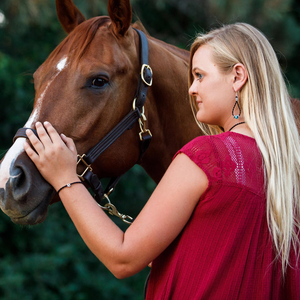 blonde woman with chestnut horse wearing maille horse hair earrings and love knot horse hair bracelet